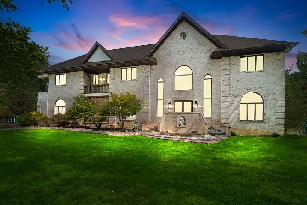 Exterior twilight shots of a stone mansion with illuminated windows and landscaped grounds.