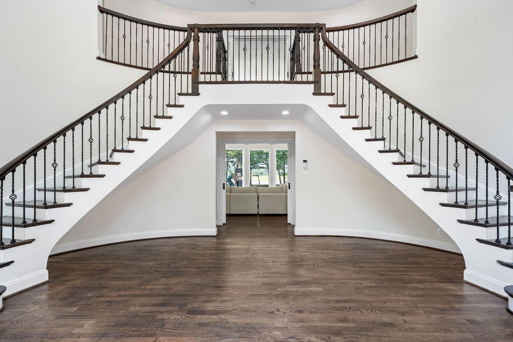 Grand staircase with dark wood steps and white railings in an open foyer space.
