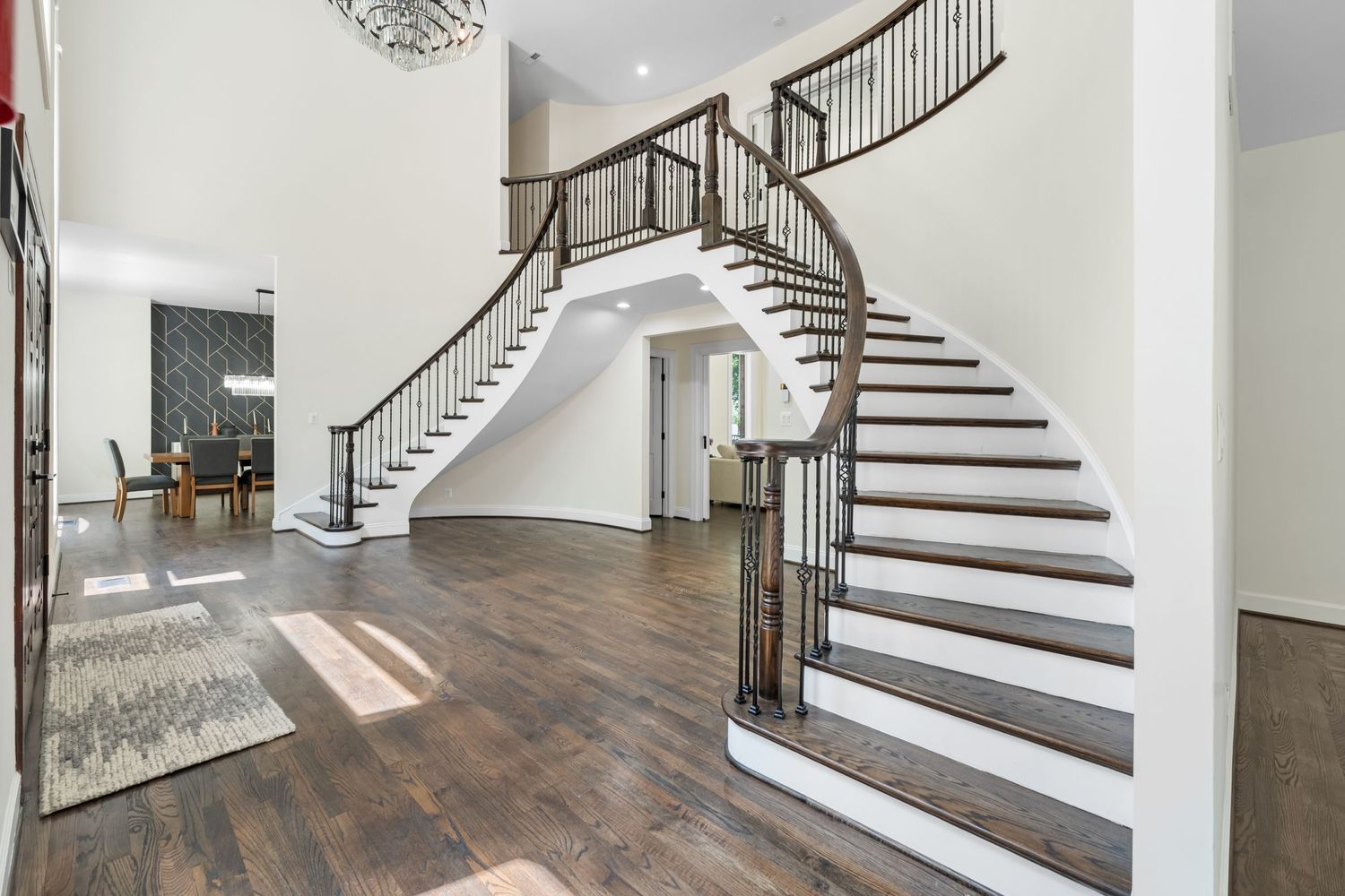 Elegant curved staircase with white risers and dark wood treads in a modern foyer.