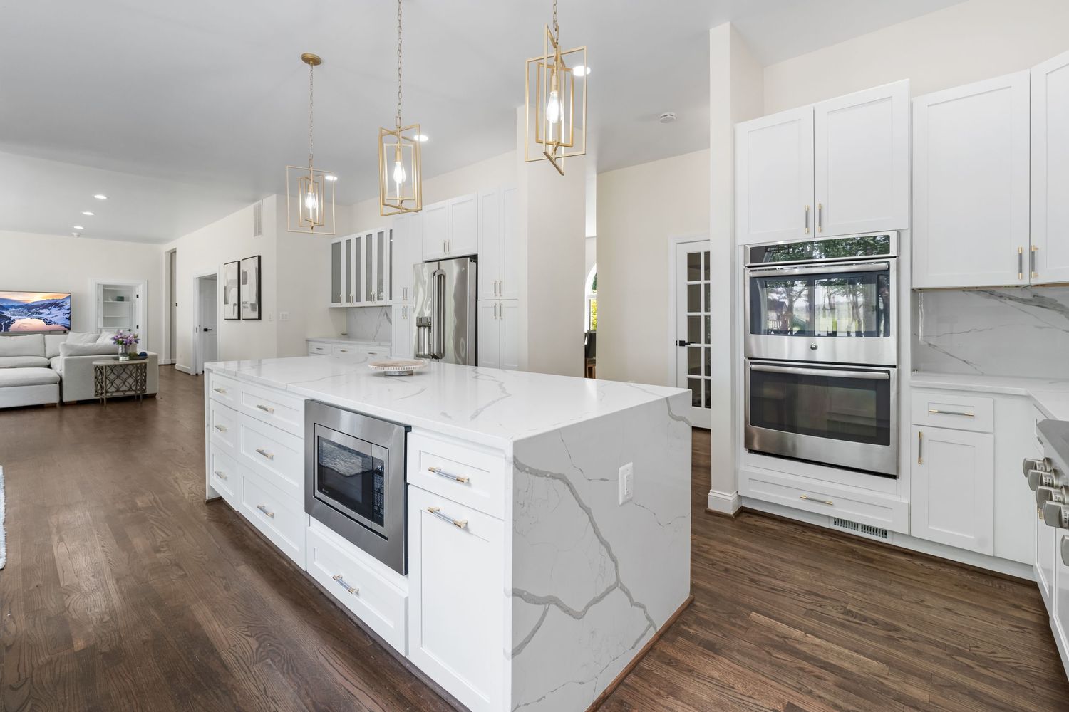 Contemporary kitchen featuring white cabinets, marble island, and pendant lighting.