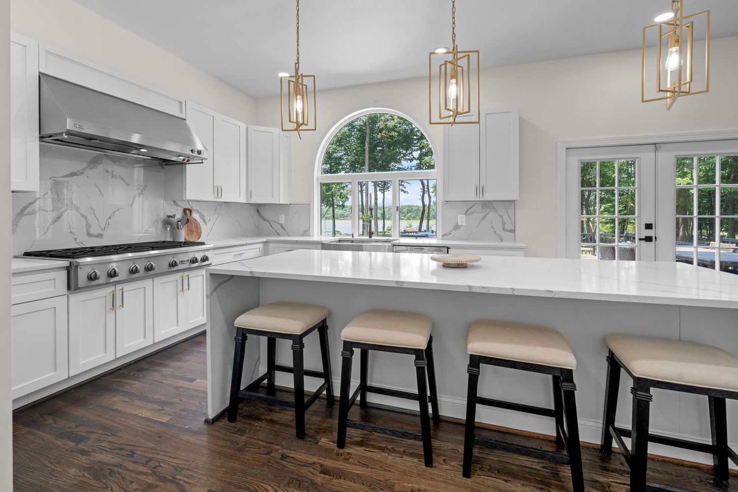Spacious kitchen with marble countertops, bar seating, and arched window detail.