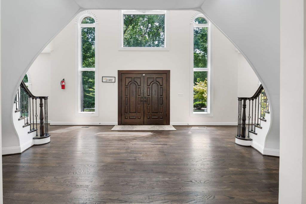 Spacious white interior foyer with hardwood floors and elegant staircase design.