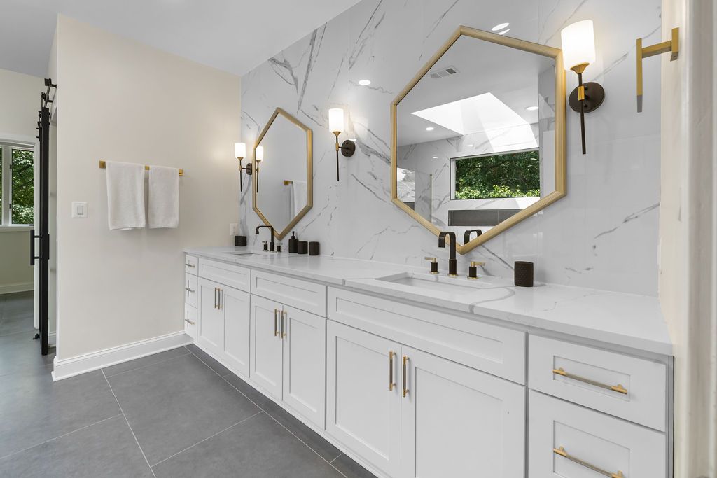 Luxury bathroom featuring marble walls, gold fixtures, and modern white vanity.