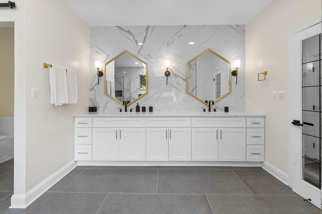 Modern white bathroom interior with double vanity, mirrors and elegant lighting fixtures.