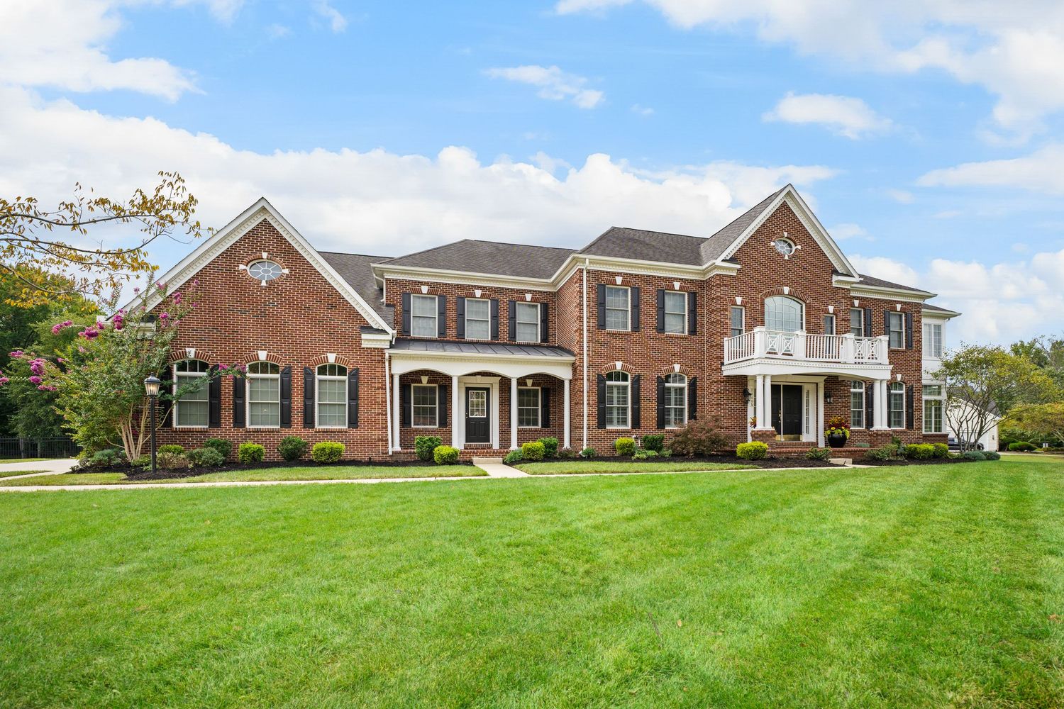 Large colonial-style brick house with symmetrical design and well-maintained landscaping.
