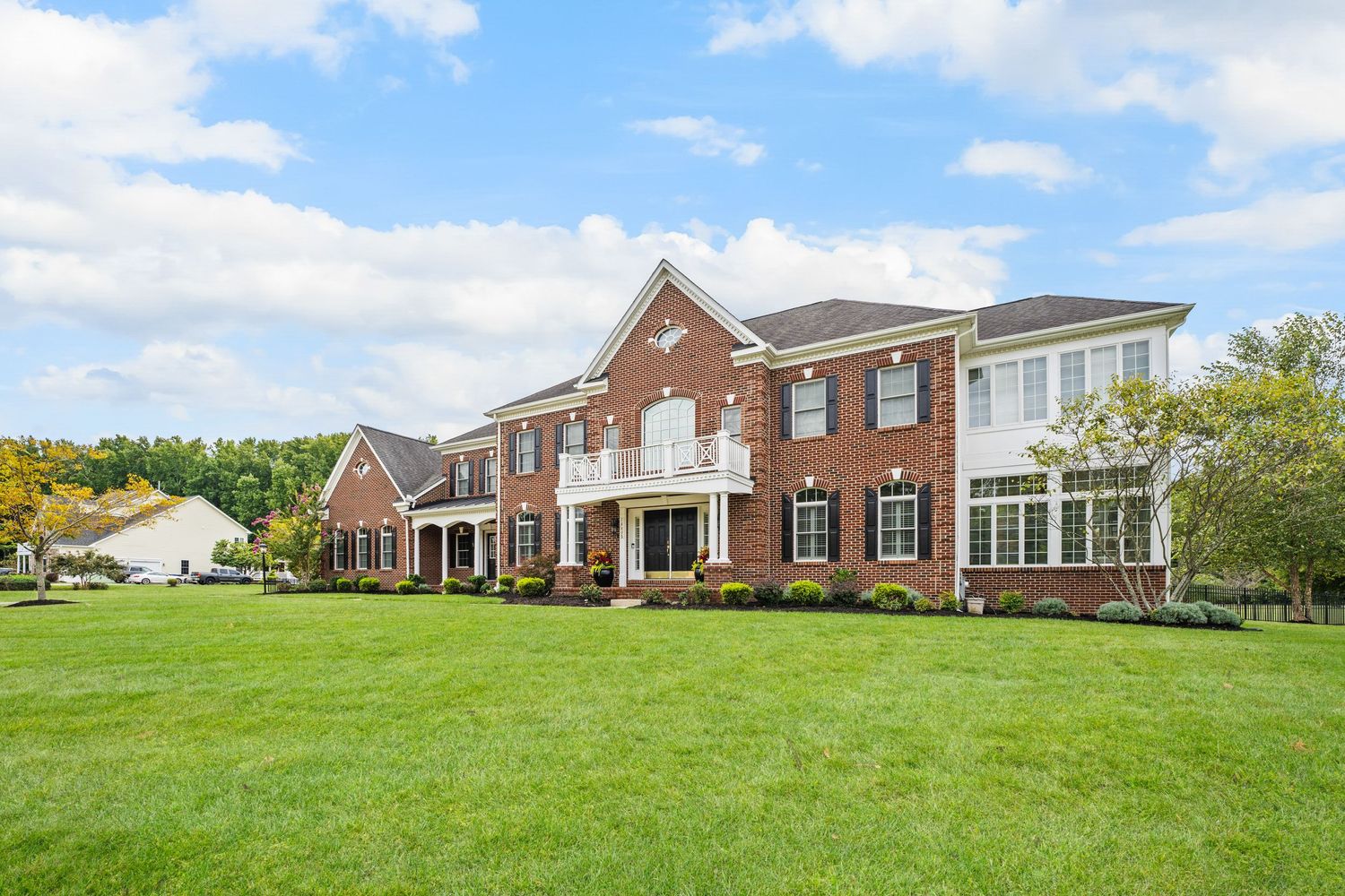 Stately brick townhouse complex with white trim and perfectly manicured green lawn.