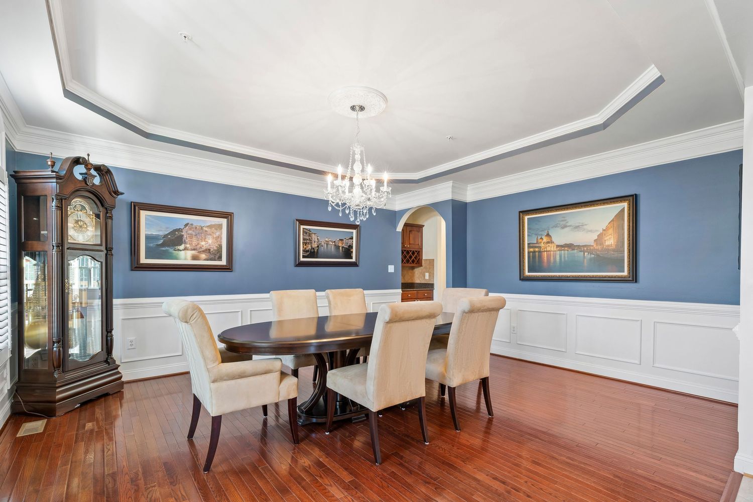 Formal dining room with crystal chandelier and blue walls showcases traditional elegance.
