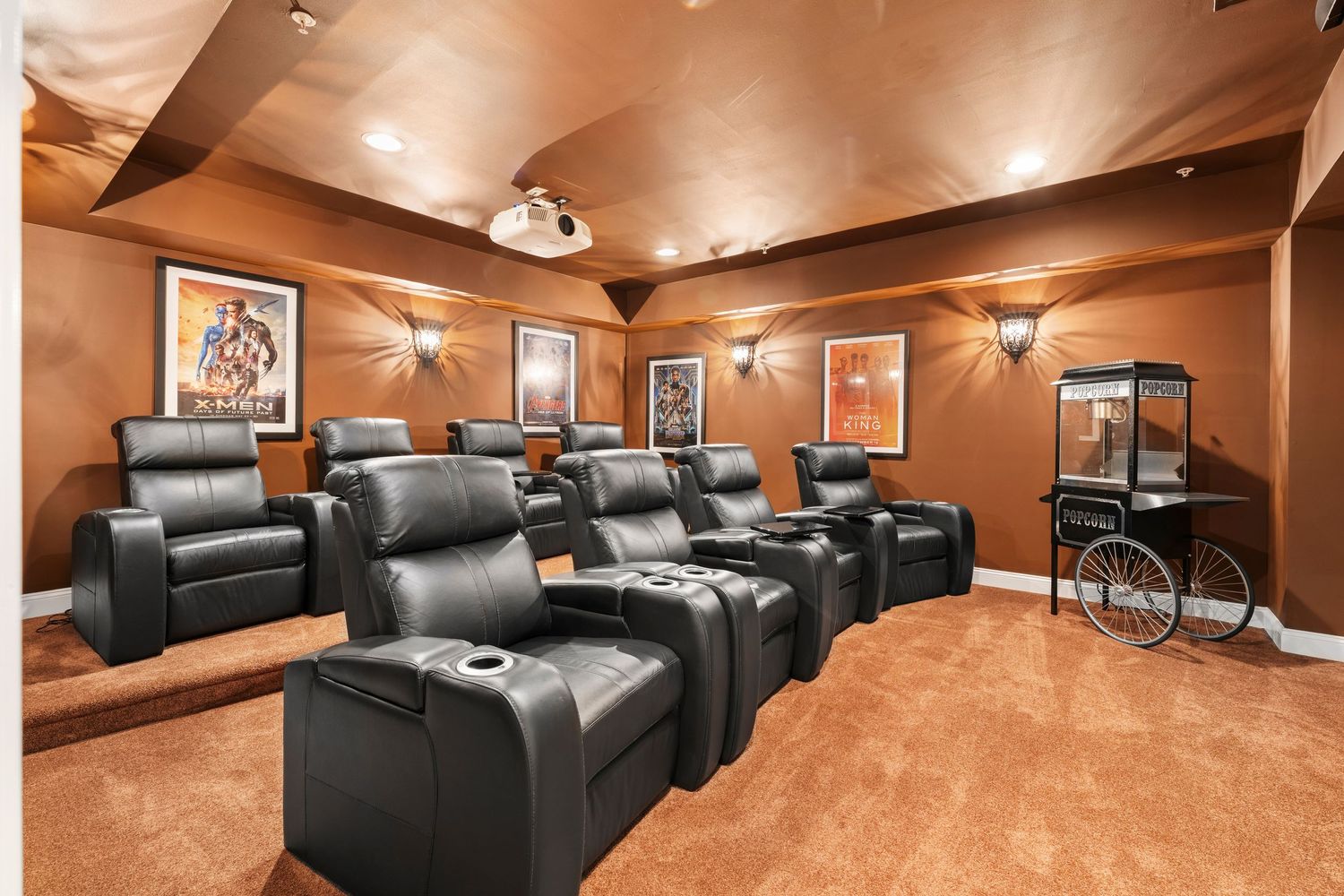 Spacious home cinema with tiered black leather recliners and ambient lighting creates a luxurious viewing experience.