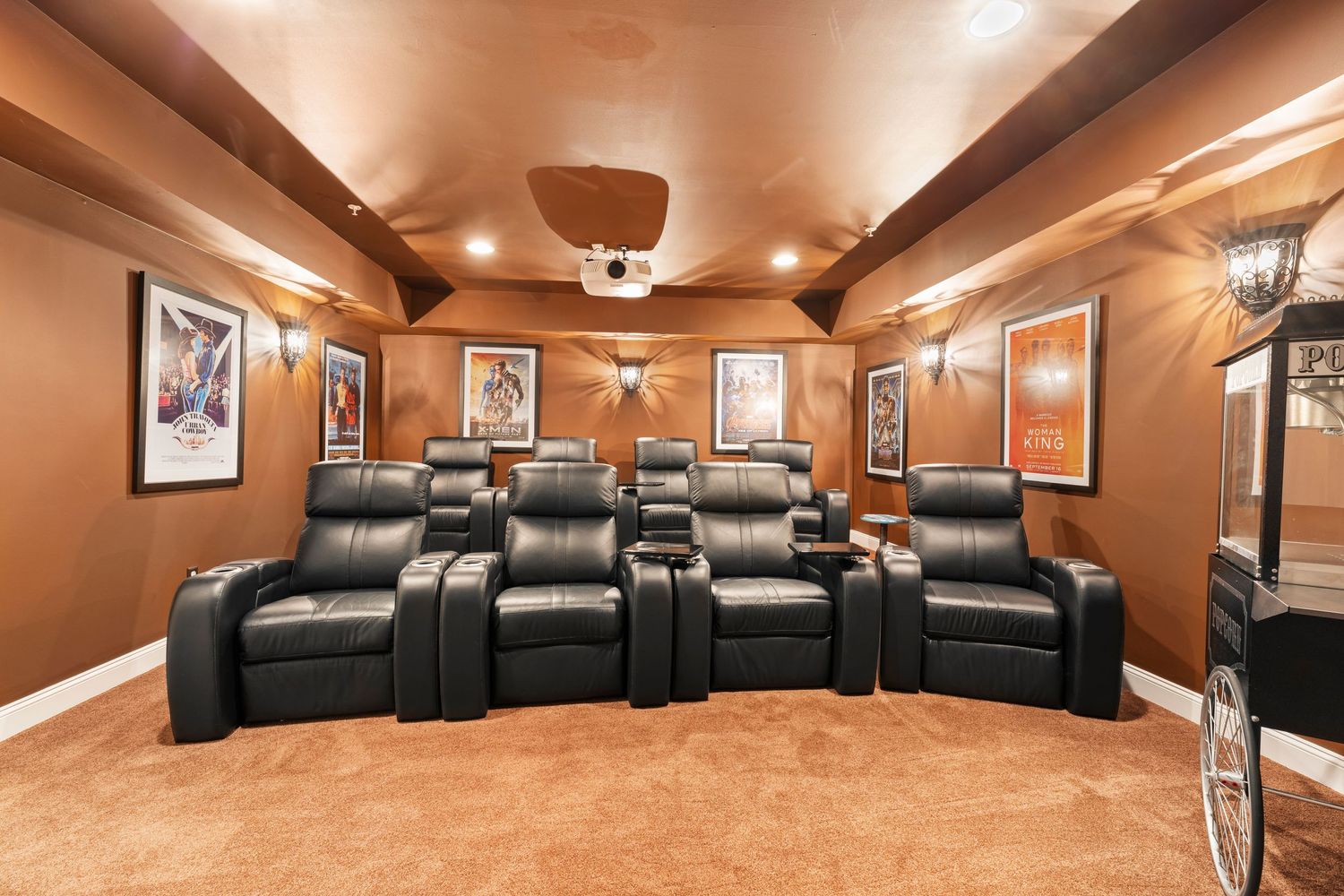 Custom home theater room features multiple rows of black leather recliners and warm lighting.