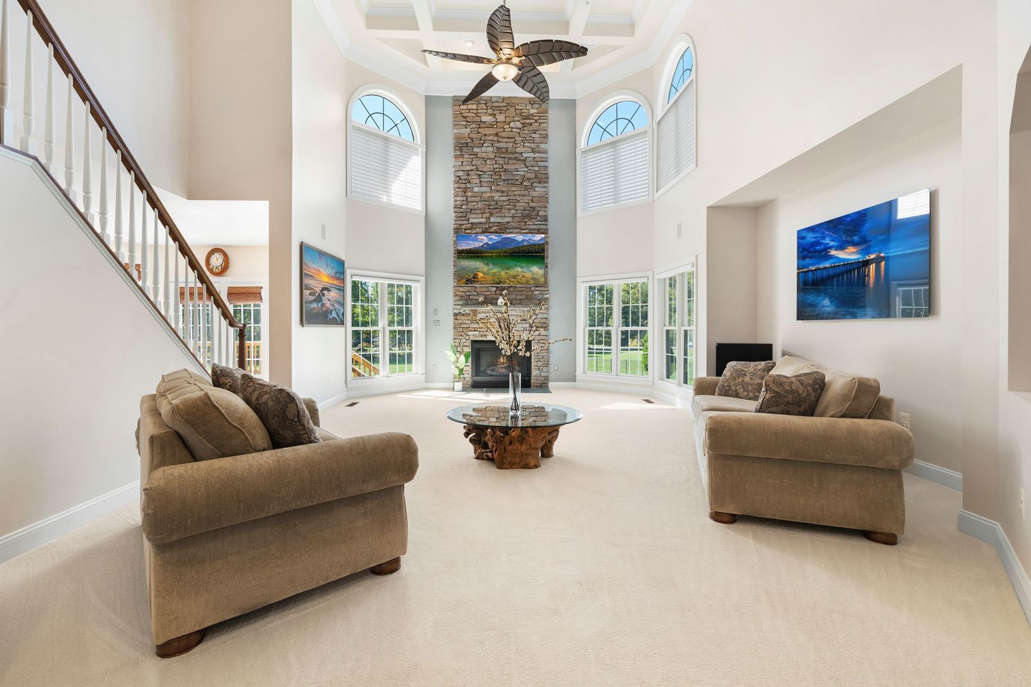 Spacious living area with arched windows and tan furniture offers comfortable seating arrangements.
