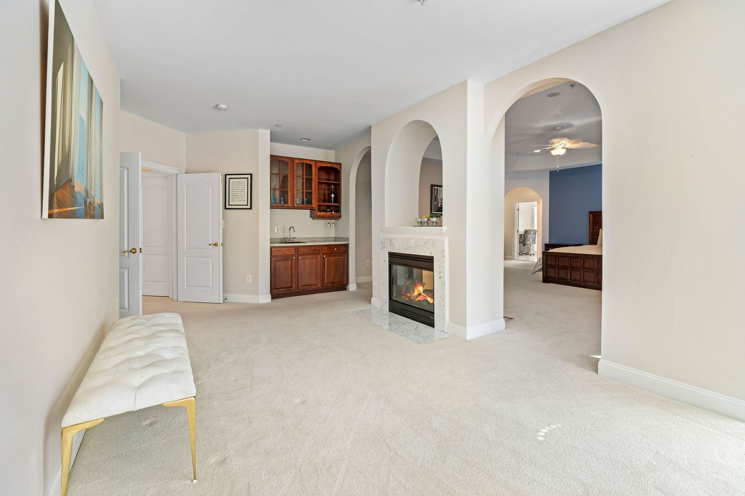 Neutral-toned living space with built-in fireplace, arched doorways, and carpeted floors.