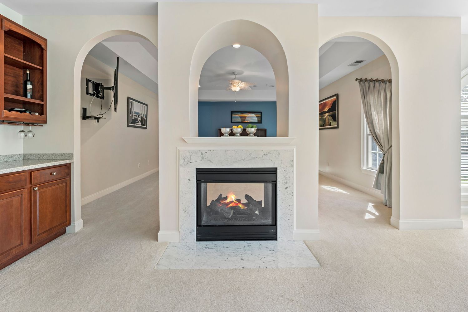 Elegant hallway with white arched doorways and hardwood floors showcases classic architectural details.