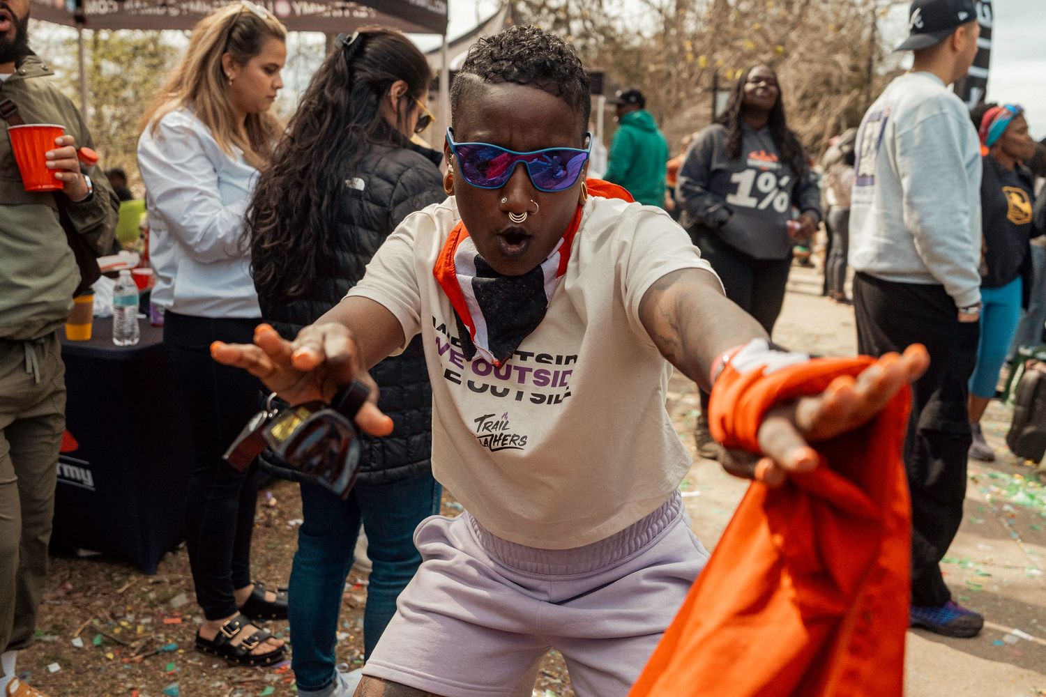 Person in sunglasses and white t-shirt energetically dancing outdoors at a social gathering event.