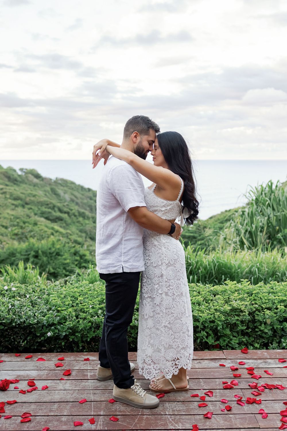 A couple embracing each other in a romantic setting surrounded by greenery.