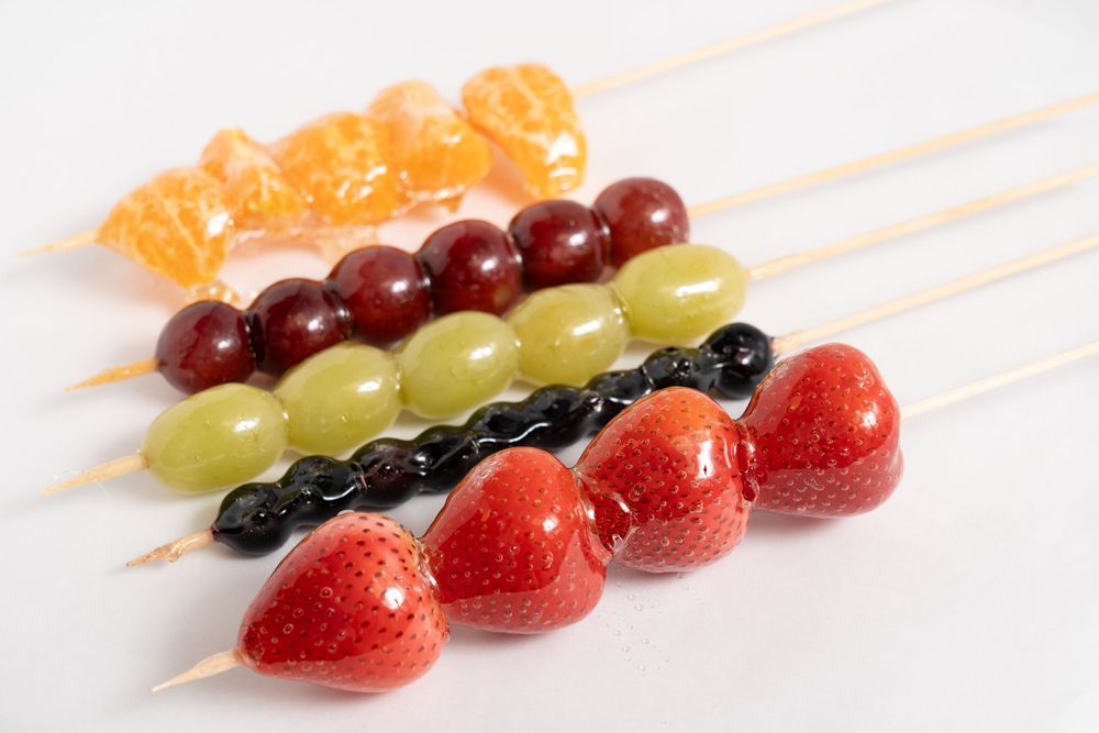 Colorful fruit skewers with strawberries, grapes, oranges and blueberries.