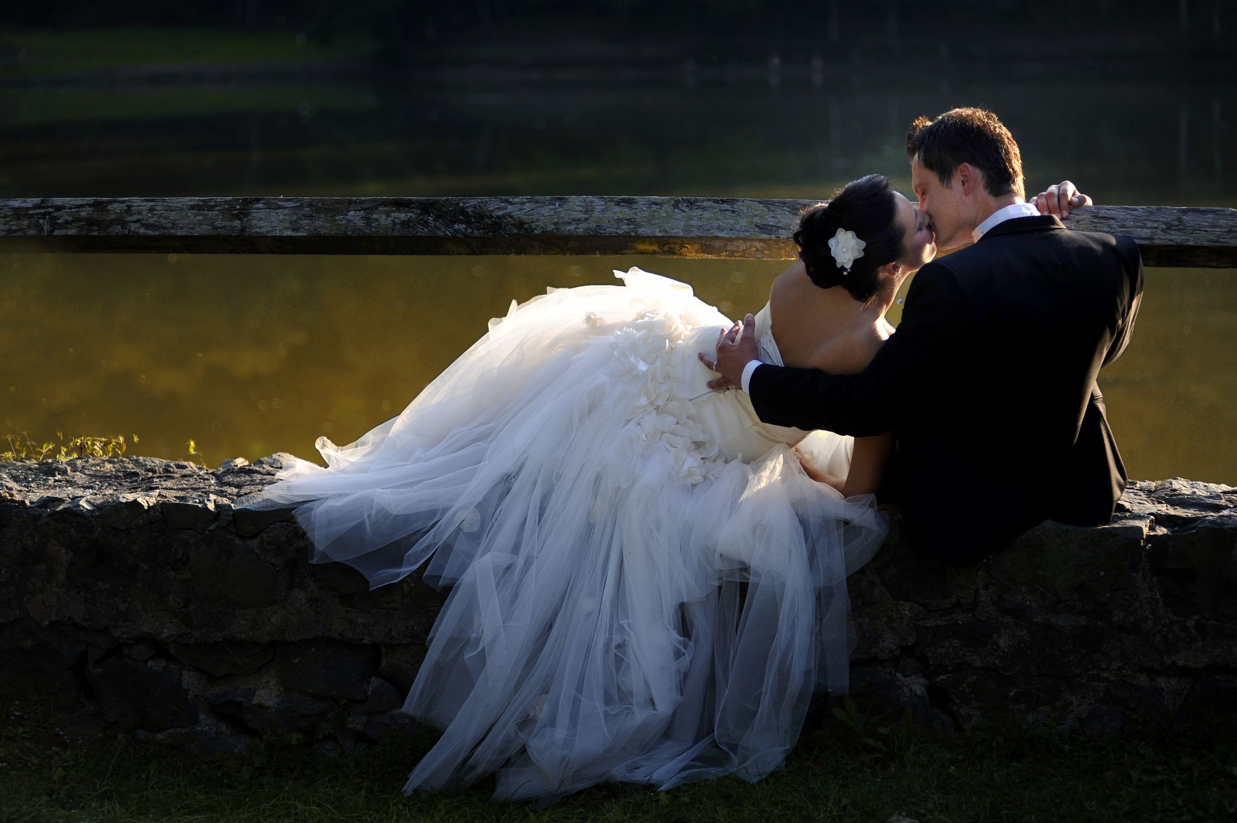 Black and white overhead photo of a couple in formal wedding attire lying down and smiling together.
