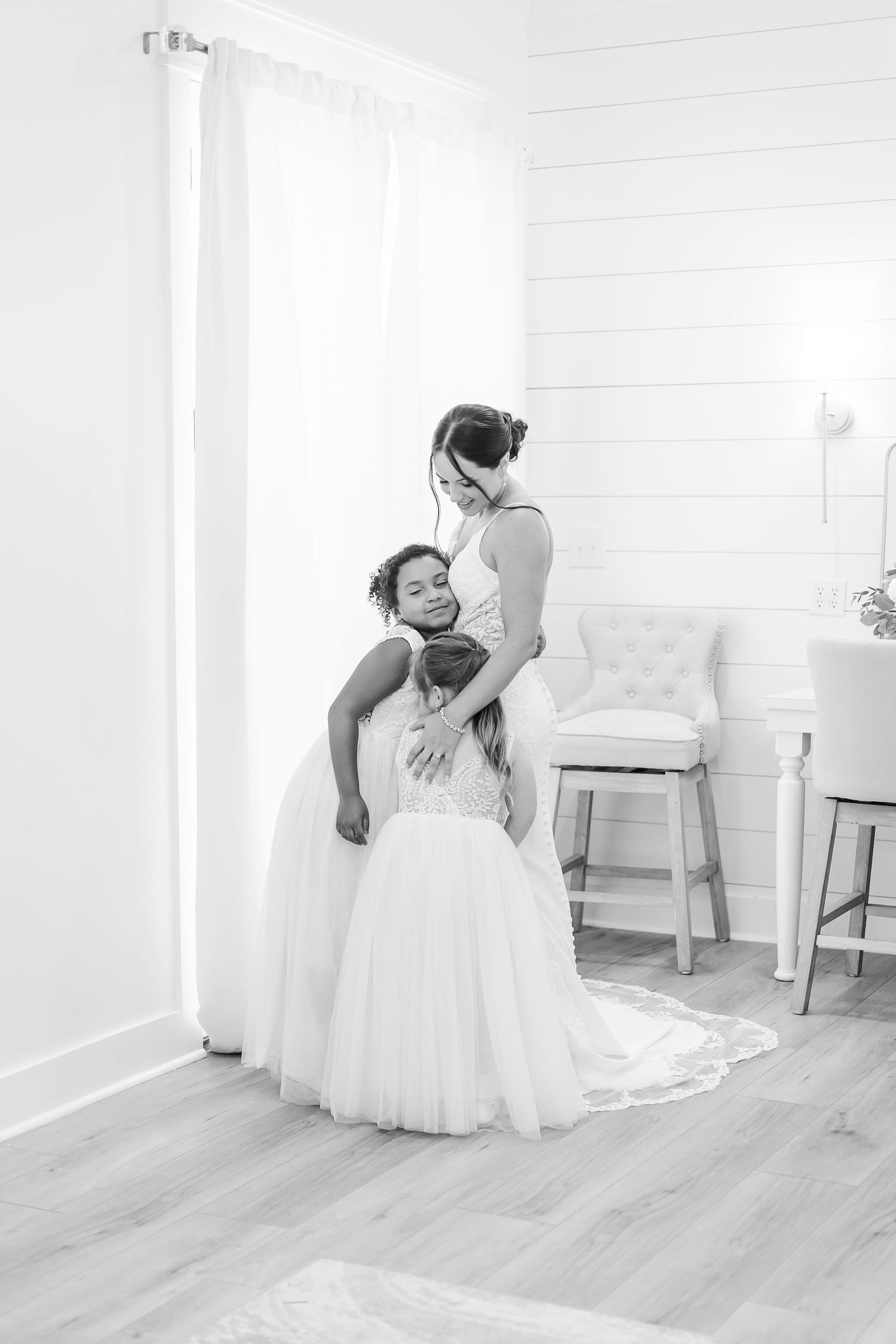 Black and white wedding photography session in bright white room with wooden floors.