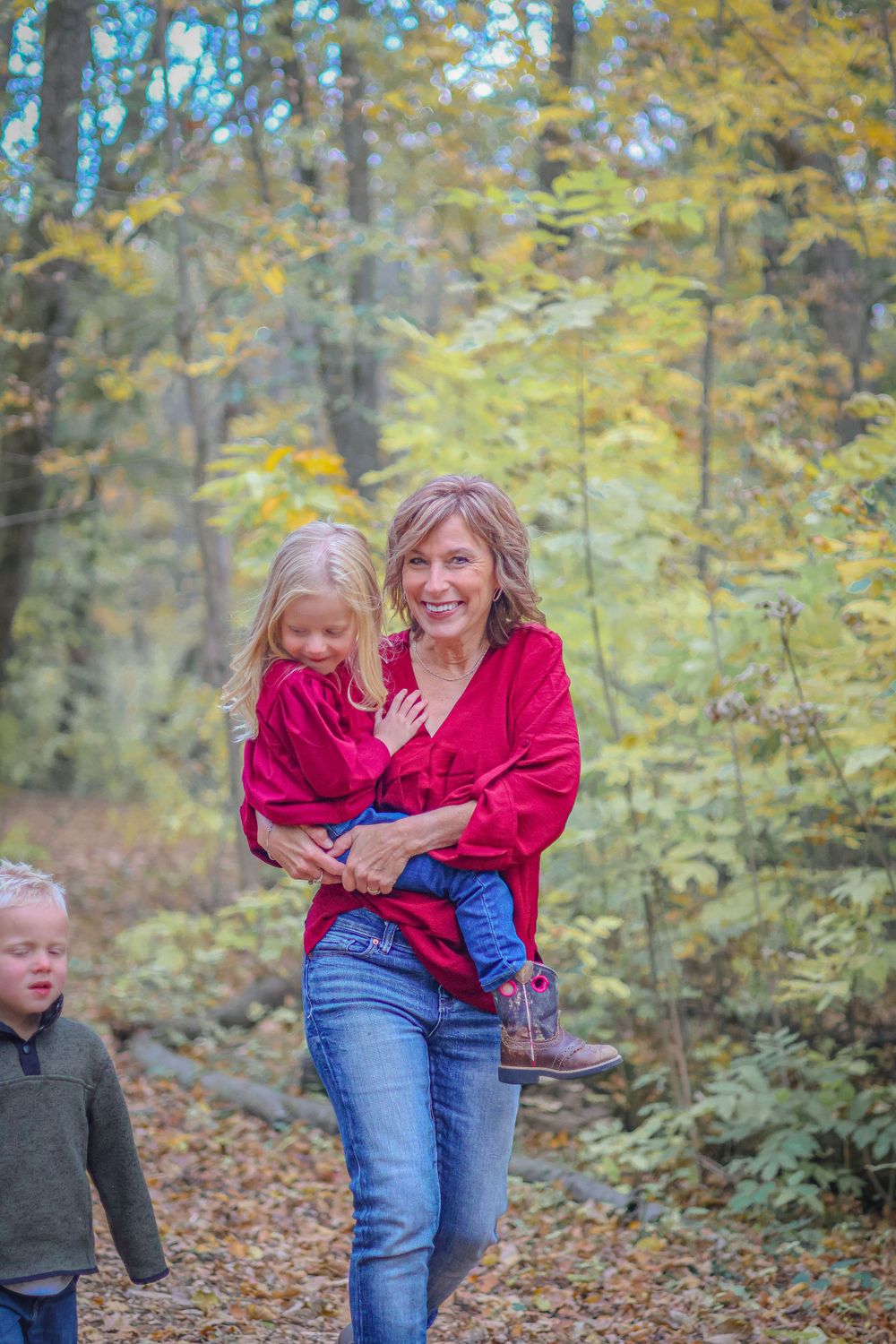 Autumn family photoshoot in wooded setting with falling leaves.