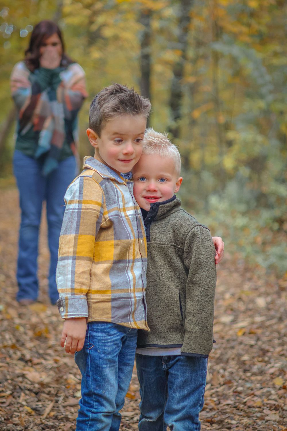 Children hugging with autumn foliage in background.