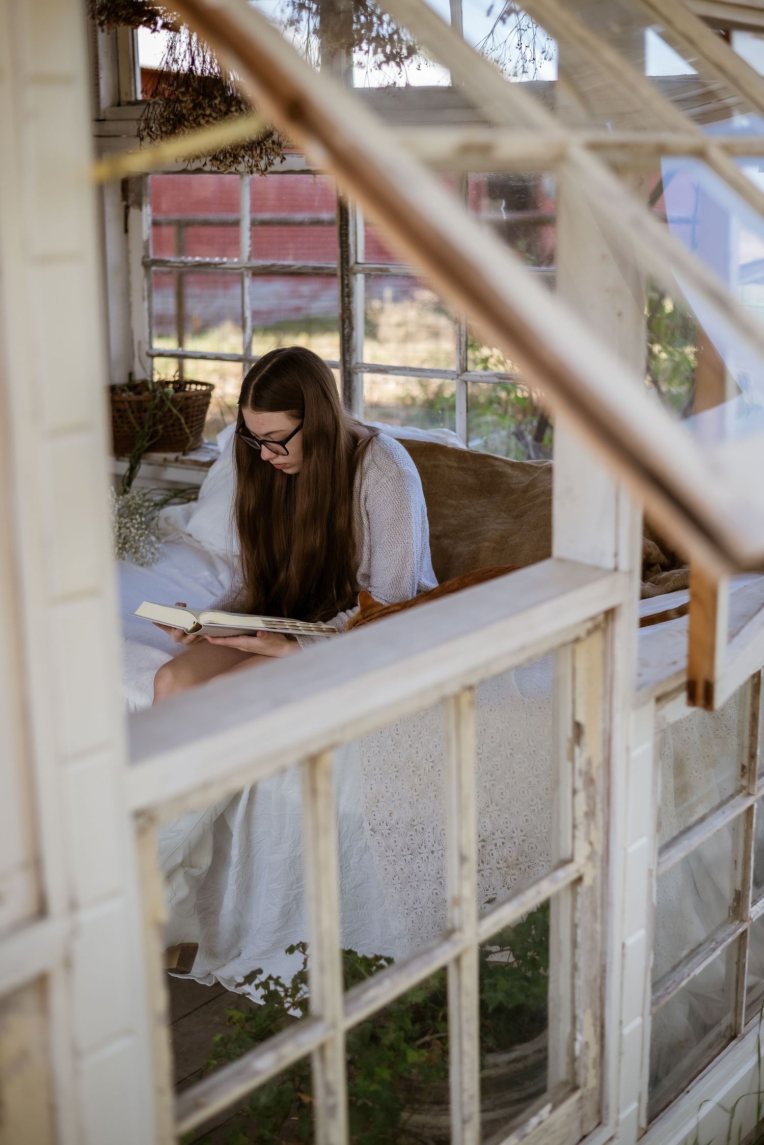 Person in white sitting on a weathered porch railing during golden hour.