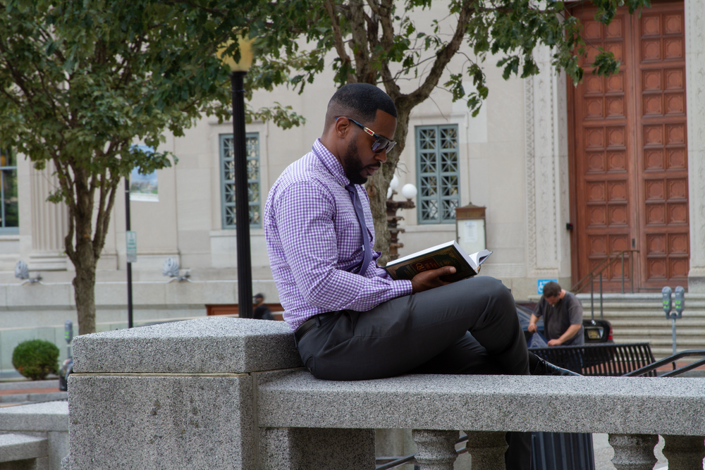Professional sits outside on stone steps while reading.  L Visions Photography. Lifestyle photoshoot. Brandin photoshoot.