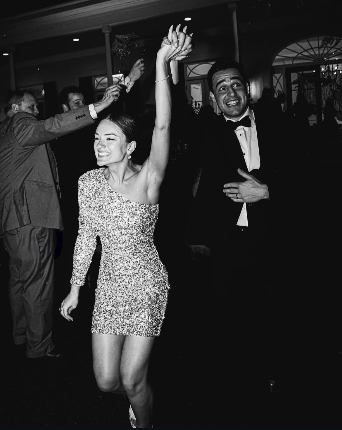 Black and white photo of people dancing and celebrating in a dimly lit venue.