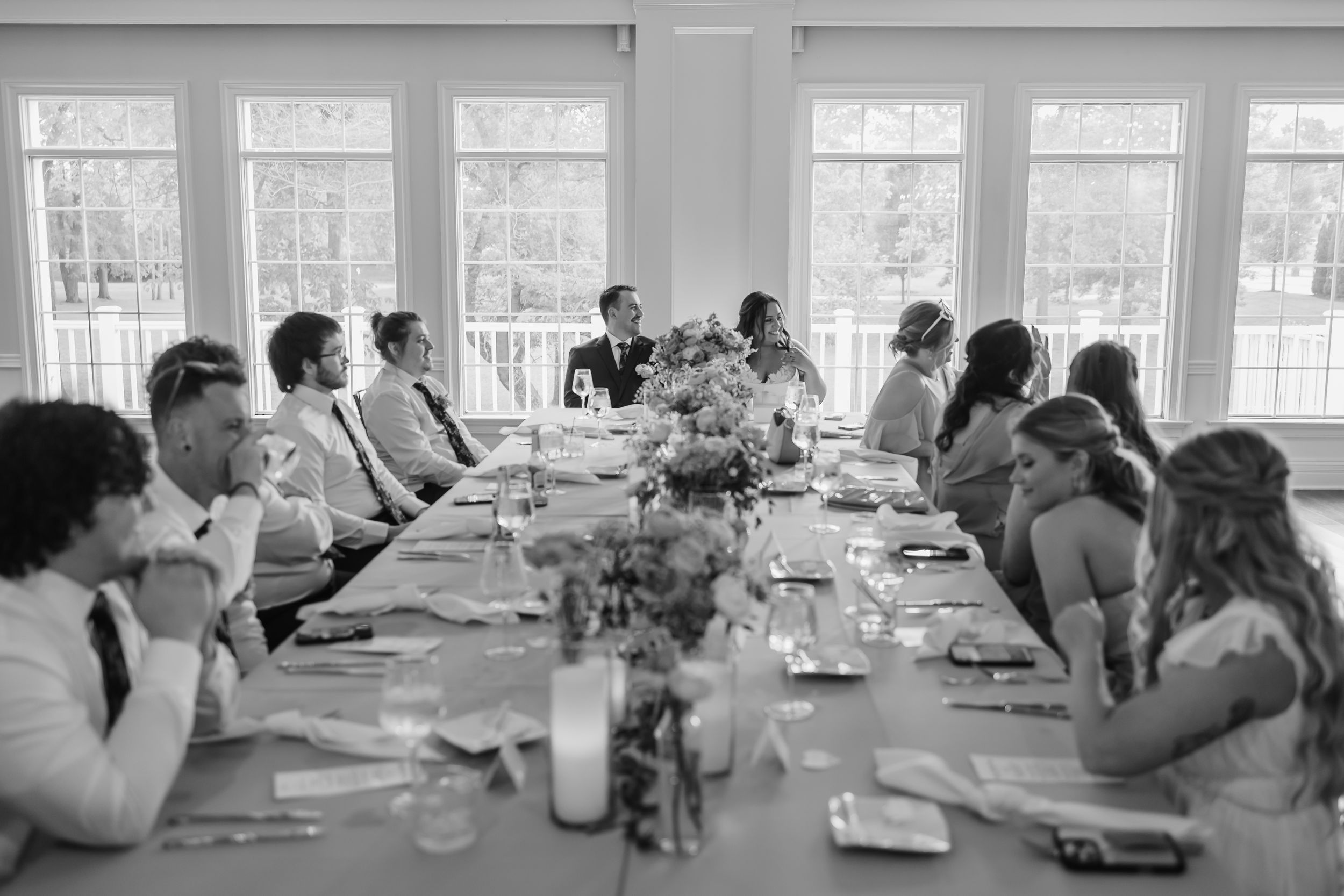 People gather around long tables in a bright meeting room for a workshop or conference session.