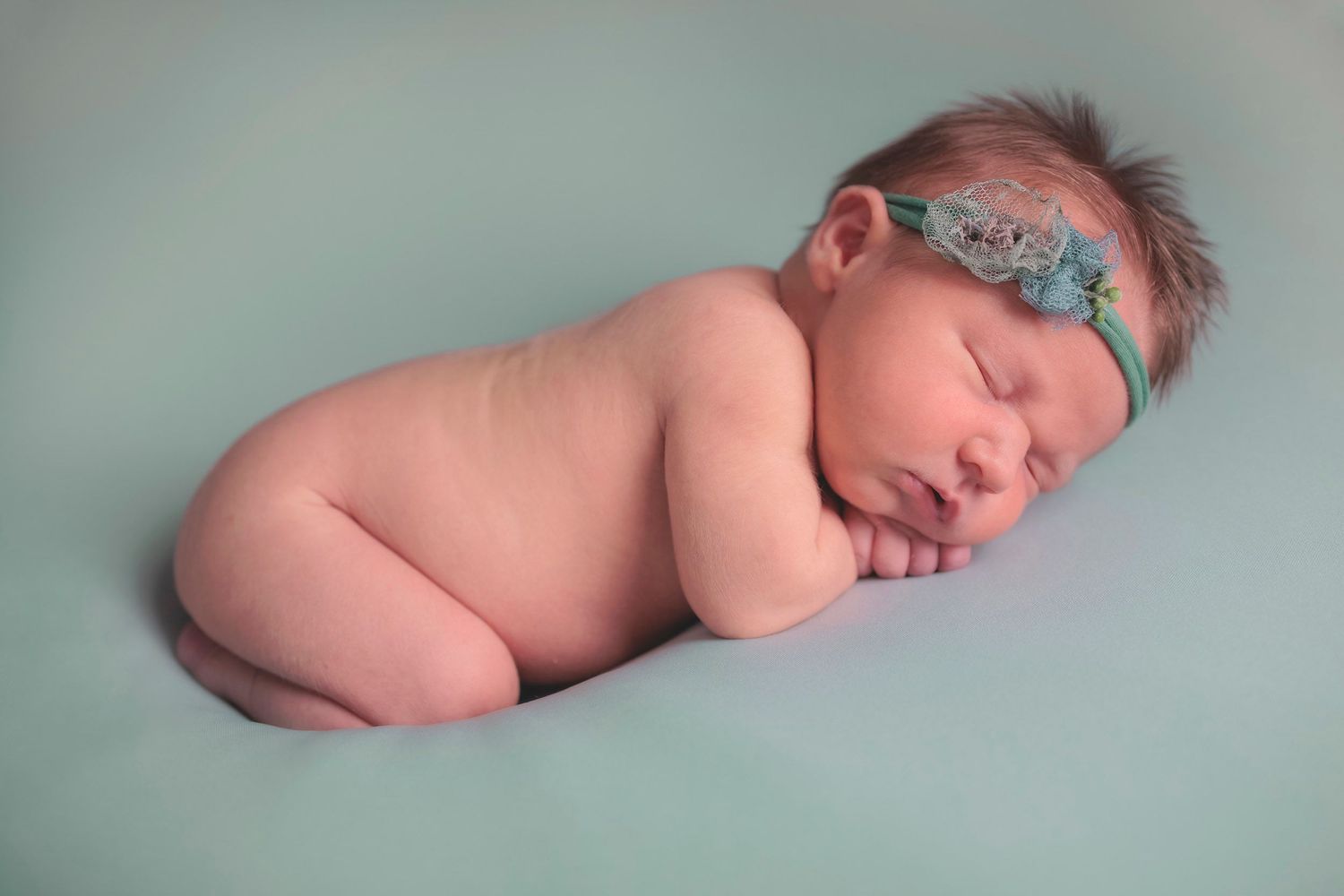 Sleeping newborn baby wearing teal headband. Baby first portrait, newborn photos, Gosport newborn photography in Hampshire photo studio.