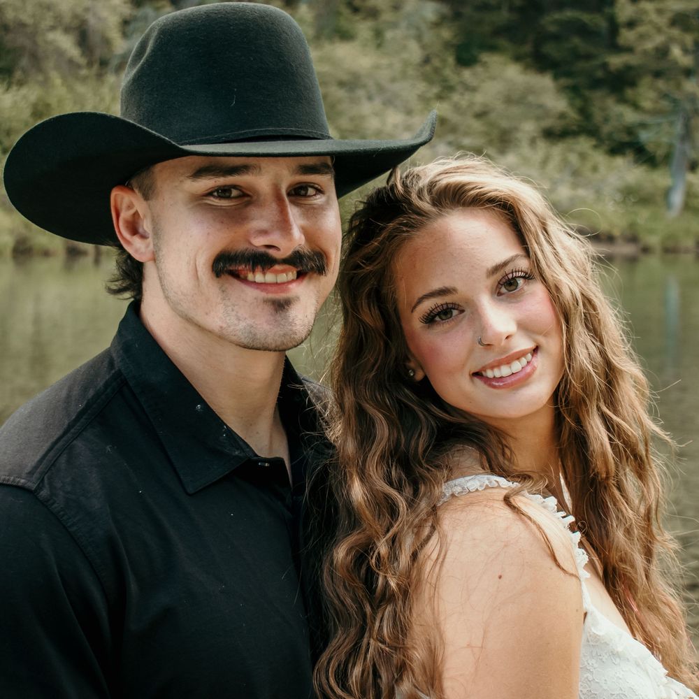 A romantic couple in western attire shares intimate moments against a scenic mountain backdrop.
