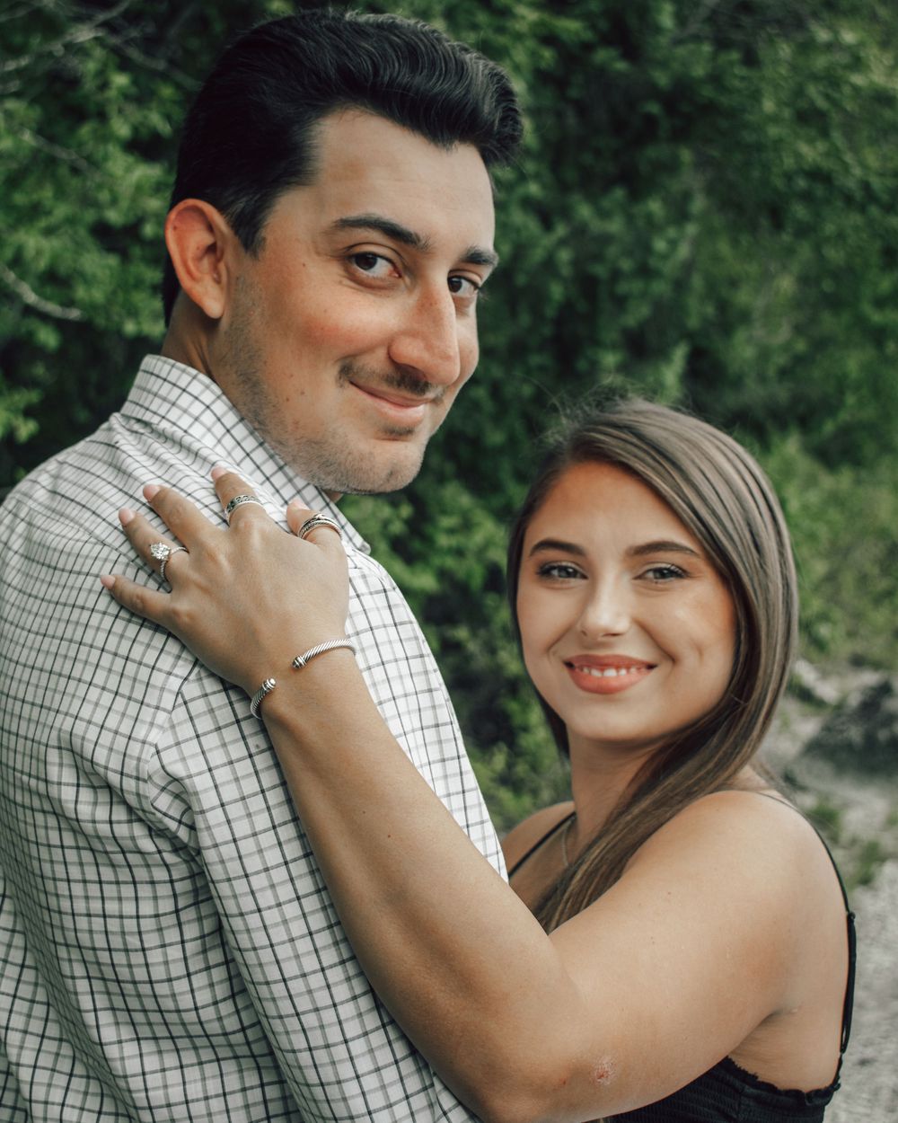 A romantic couple shares tender moments in an outdoor photoshoot series against a lush green background.