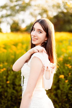 A Stoughton High School senior posing with her pointe shoes in a field in Weymouth MA