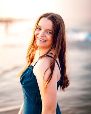 A Scituate High School Senior posing and smiling in the water at Rexhame Beach in Marshfield MA