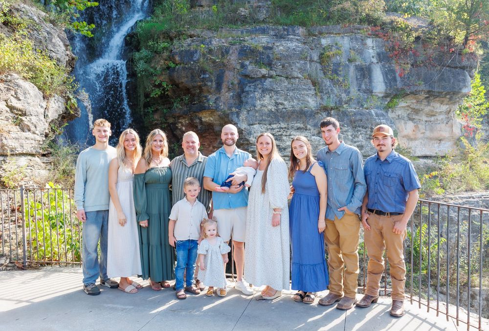 Family group portrait session at scenic waterfall location wearing coordinated blue and neutral colored outfits.