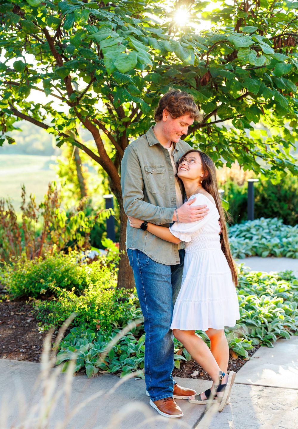 A couple shares a romantic moment in a lush garden setting during a golden hour photoshoot.