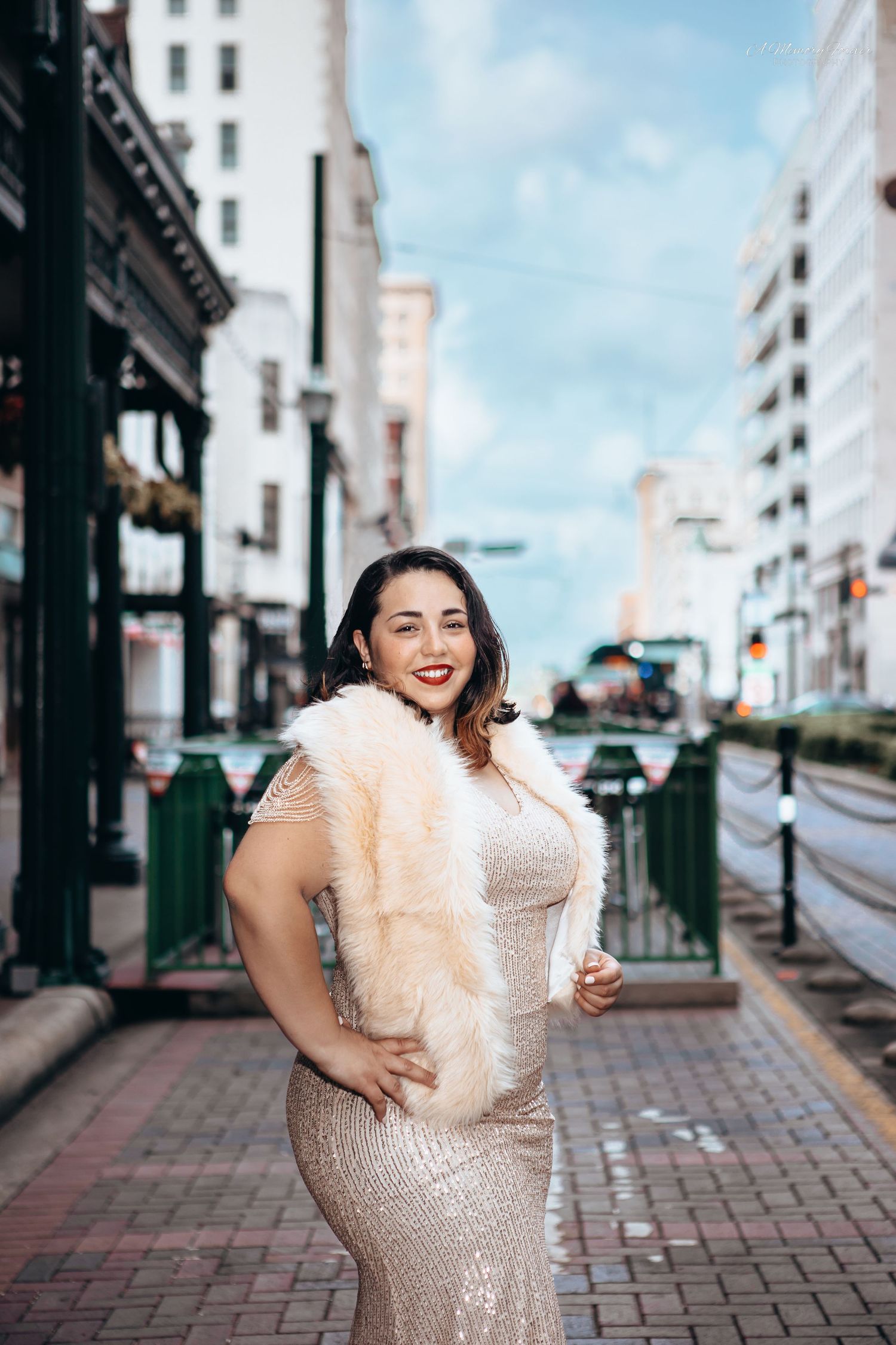 Plus-size woman in sequin gown and fur stole poses confidently on urban city street.