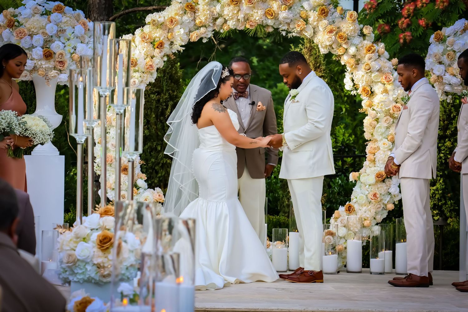 Wedding ceremony under beautiful floral arch with white and peach roses.