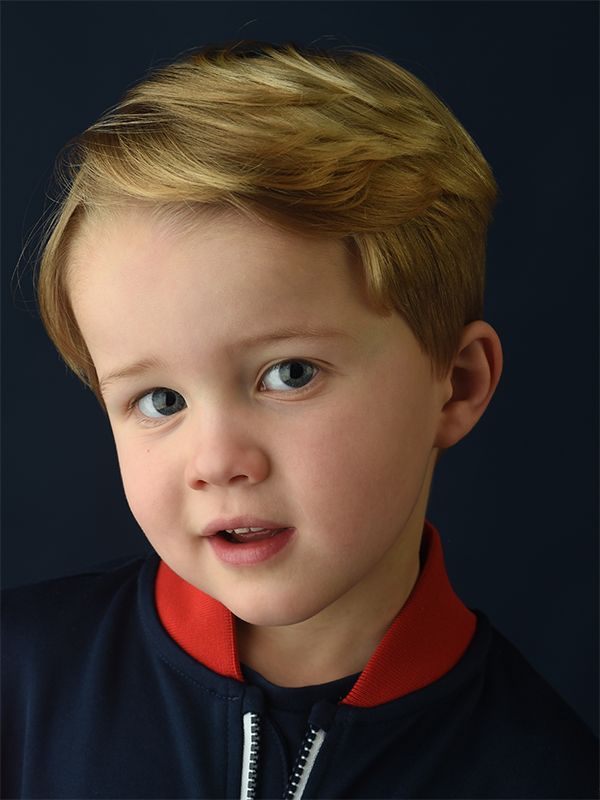 In a family portrait at Abigail's Studio, a young boy with blonde hair and blue eyes smiles brightly at the camera.