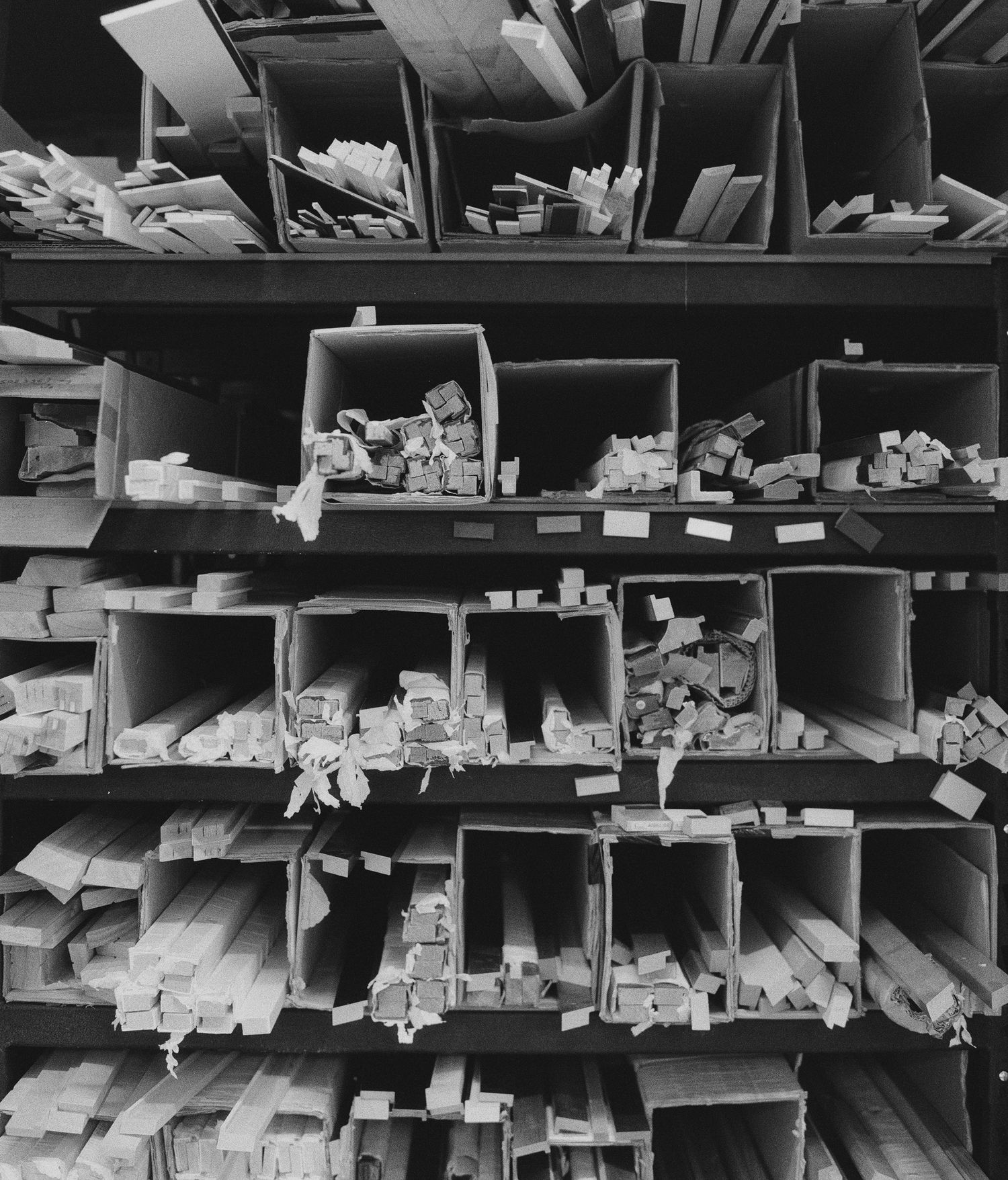 Black and white photo of a wall in the Atkins Pro Lab, showing paper scraps, wood pieces, and various materials in storage.