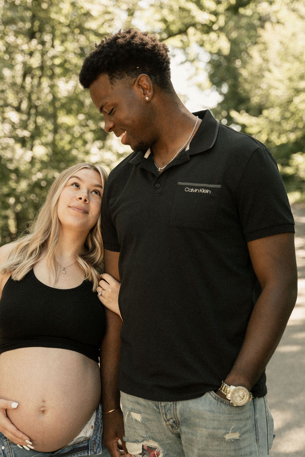 A couple shares intimate moments in a series of outdoor maternity photos showing a growing baby bump.