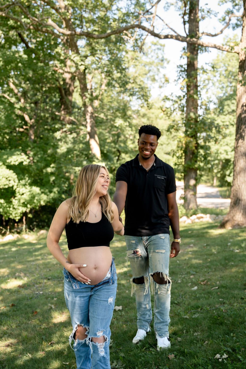 A couple shares a joyful moment together while walking through a sunny park on a warm afternoon.