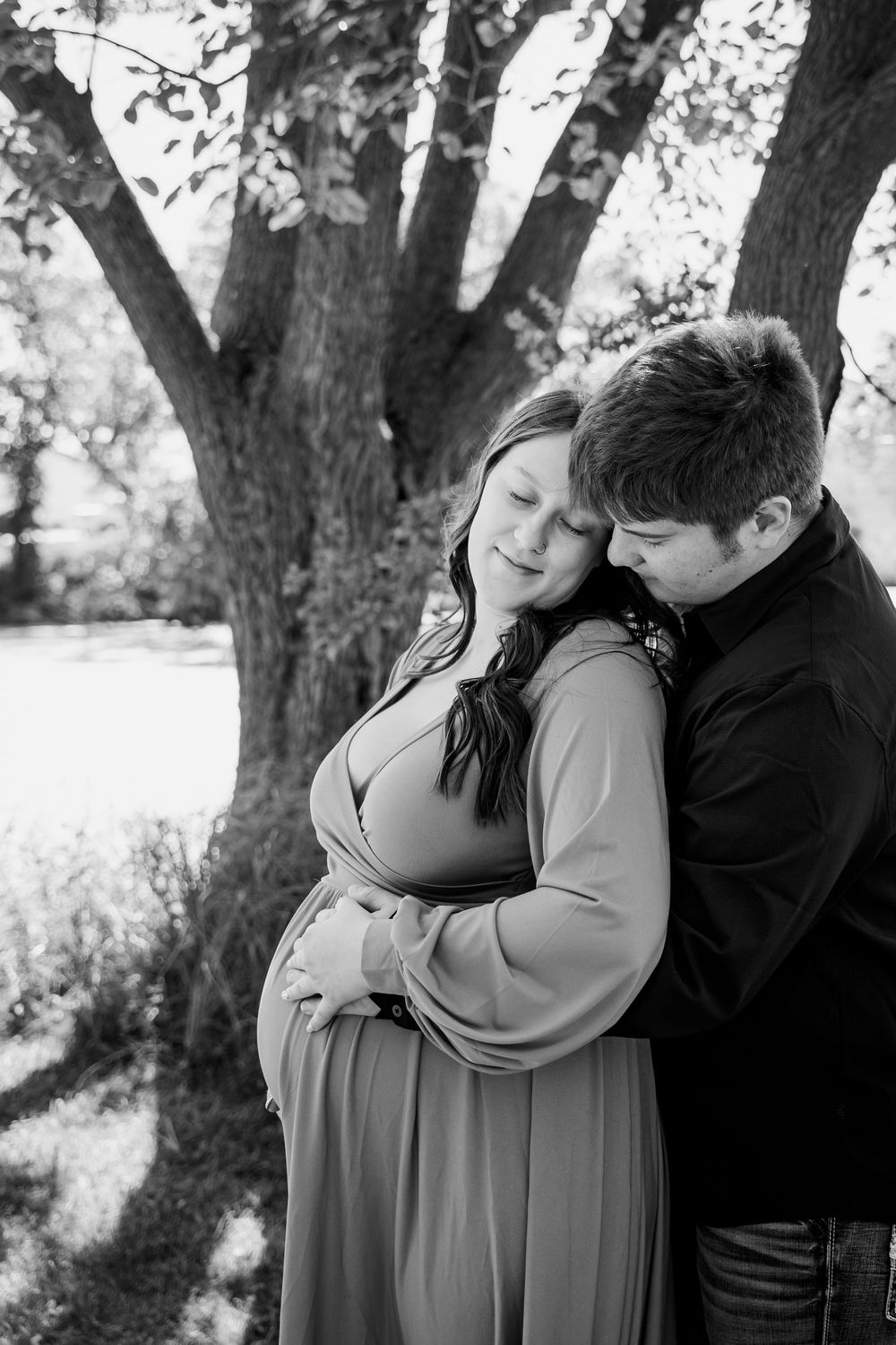 A black and white portrait of an intimate moment between a couple during a maternity photoshoot.