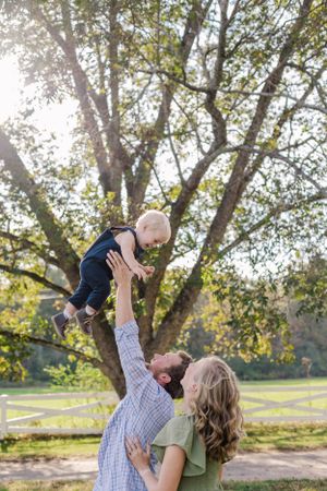 A playful family moment captured during sunset beneath a towering tree.