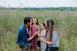 Loving family shares joyful moments together in a tall grass field during sunset.