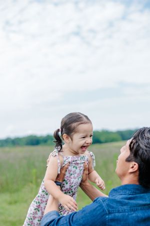 Playful moment captured between parent and child in a sunny meadow.