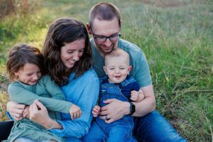 A family shares a joyful moment together while sitting in a grassy field.
