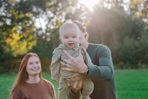 A joyful family moment photographed in a sun-drenched green field.