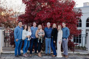 Family group portrait in front of a vibrant red maple tree during autumn.