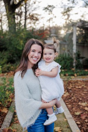 Sweet outdoor family moment captured in fall with autumn leaves on ground.