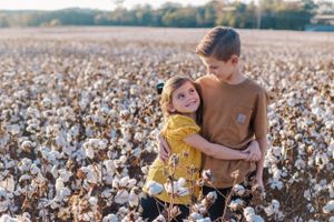 An intimate autumn portrait amongst fluffy cotton plants in a field at sunset.