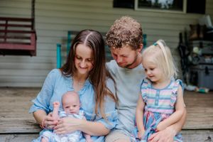 Family shares a tender moment together sitting on their front porch on a sunny afternoon.